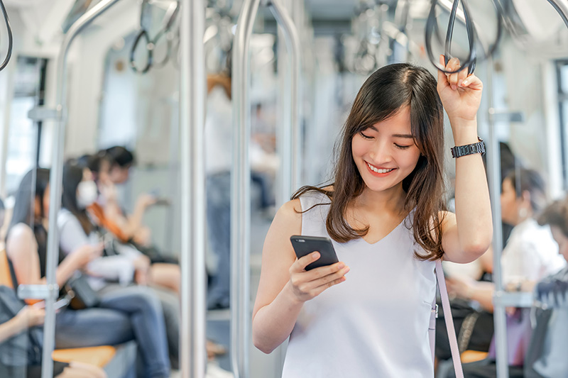 電車内でスマートフォンを楽しそうに見ている女性